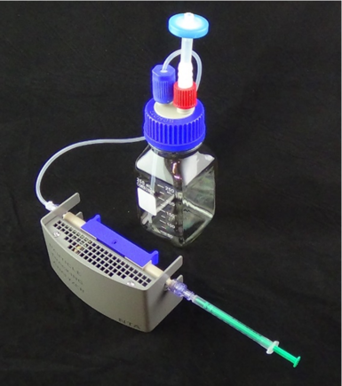 Figure 1: Standard NTA Cell Assembly with blue cell holder, sample syringe and waste outlet.